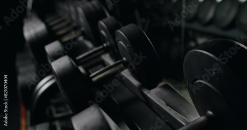 Close-up shot of a focused athlete's hand selecting dumbbells from a gym rack, illustrating dedication and strength in fitness training. Focused Athlete Preparing for Workout Selecting Dumbbells photo