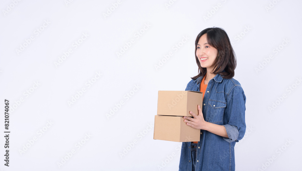 young asian woman wearing orange t-shirt and denim shirt holding parcel box isolated on white studio background, Delivery courier and shipping service concept. young asian woman wearing orange t-shirt and denim shirt holding parcel box isolated on white studio background, Delivery courier and shipping service concept.