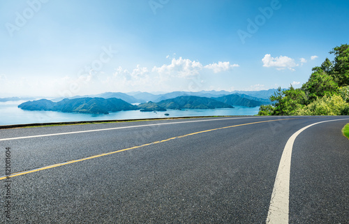 Asphalt highway road and lake with islands nature landscape on a sunny day. Beautiful coastline in summer season.