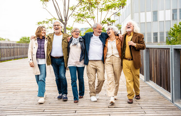 Happy group of senior people walking outdoors - Laughing aged friends having fun on city street