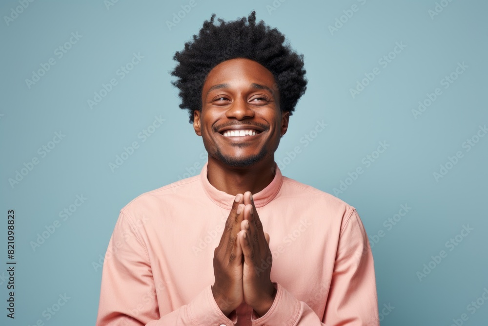 Portrait of a tender afro-american man in his 20s joining palms in a gesture of gratitude on solid color backdrop Portrait of a tender afro-american man in his 20s joining palms in a gesture of gratitude on solid color backdrop