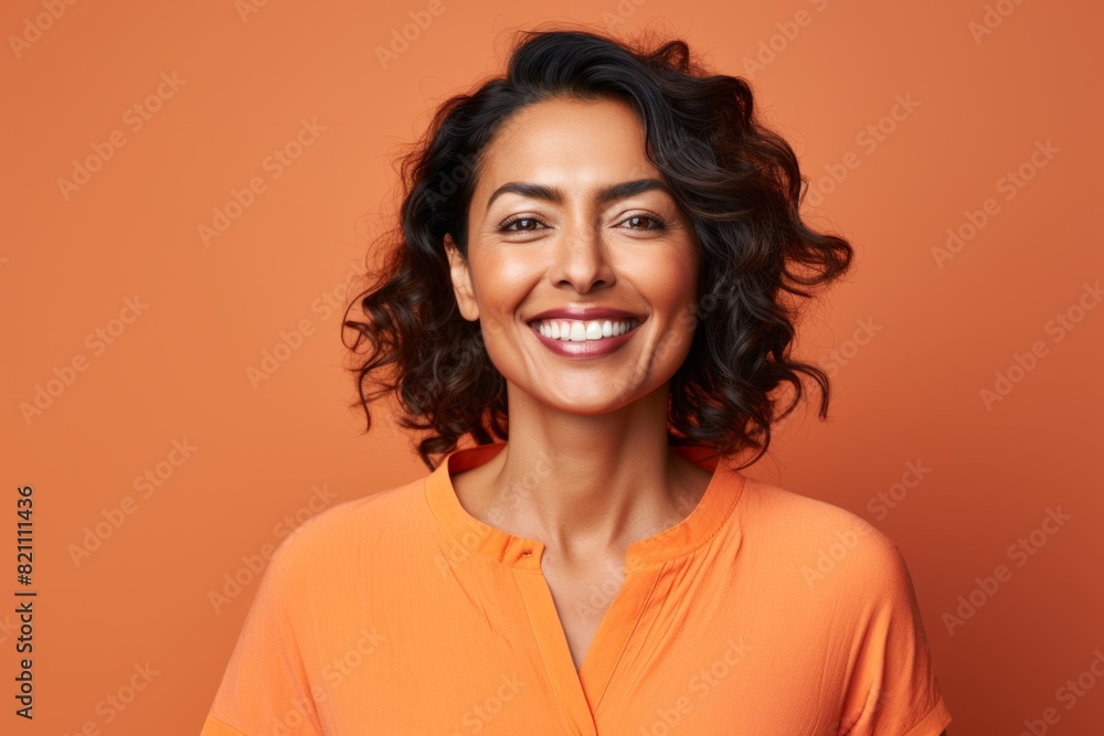 Portrait of a grinning indian woman in her 40s smiling at the camera in front of solid pastel color wall Portrait of a grinning indian woman in her 40s smiling at the camera in front of solid pastel color wall