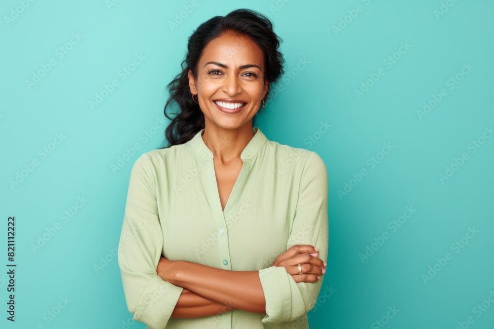 Portrait of a happy indian woman in her 40s with arms crossed isolated in solid pastel color wall Portrait of a happy indian woman in her 40s with arms crossed isolated in solid pastel color wall