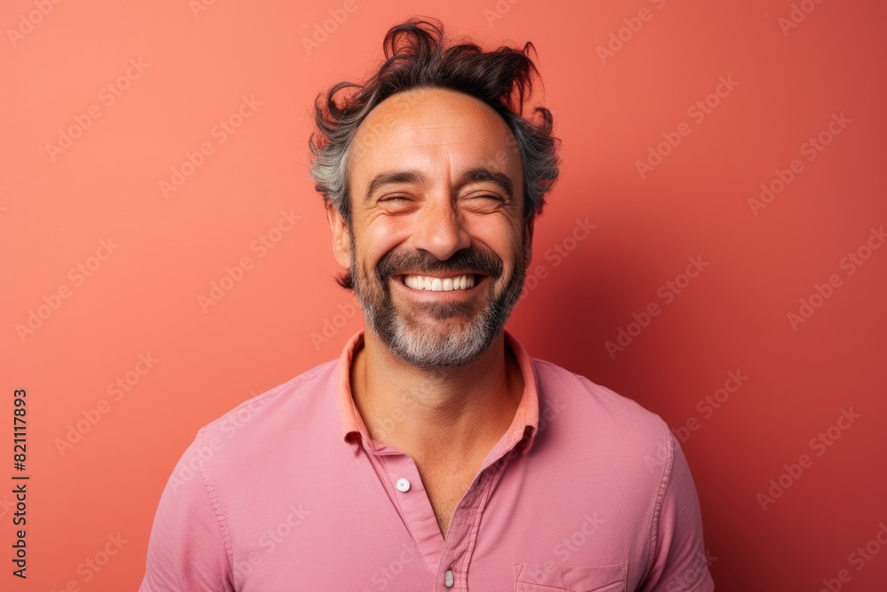 Portrait of a joyful man in his 40s smiling at the camera in solid pastel color wall Portrait of a joyful man in his 40s smiling at the camera in solid pastel color wall