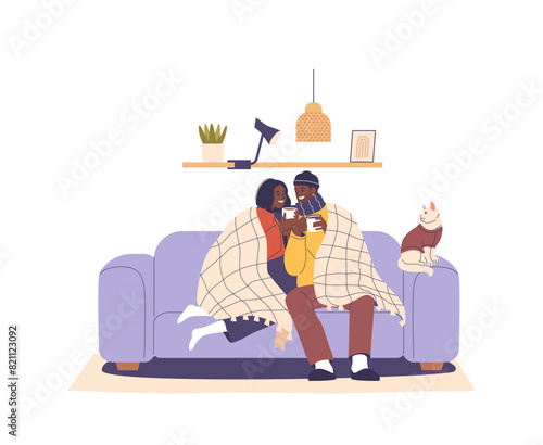 Freezing Couple Comfortably Wrapped In A Blanket On A Sofa, Enjoying Hot Beverages Together While A Cat Rests Beside