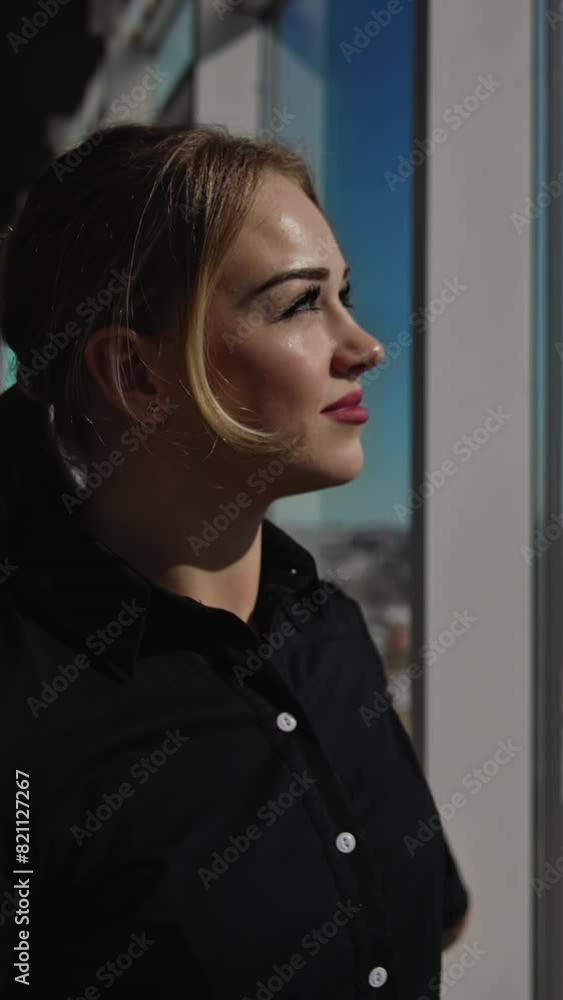 Attractive female enjoying the sunrays coming through the big panoramic window. Great look at the city from the office center. Close up with gradual distancing. Vertical video Attractive female enjoying the sunrays coming through the big panoramic window. Great look at the city from the office center. Close up with gradual distancing. Vertical video