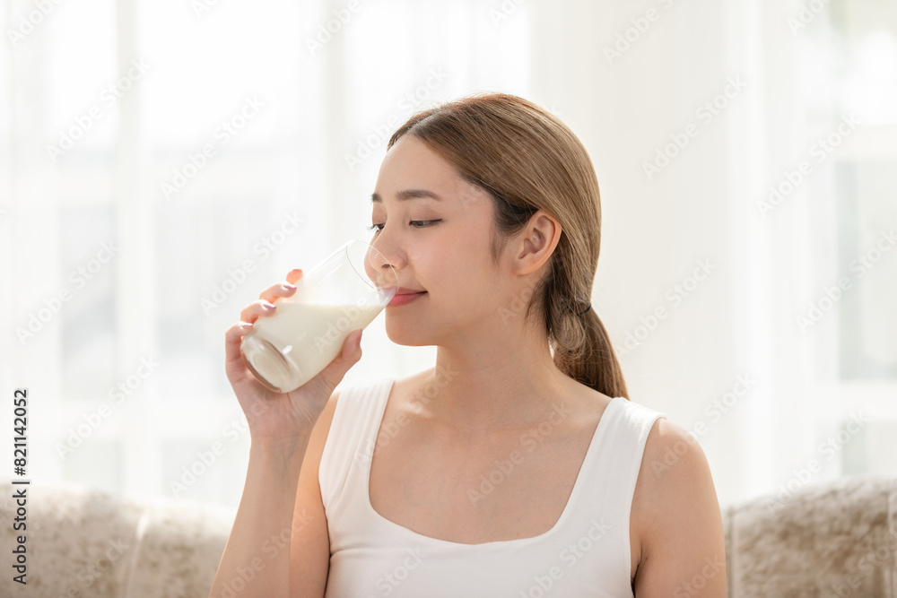 A woman enjoys a glass of milk in a bright, airy room, promoting health and well-being. The serene scene conveys simplicity and freshness. A woman enjoys a glass of milk in a bright, airy room, promoting health and well-being. The serene scene conveys simplicity and freshness.