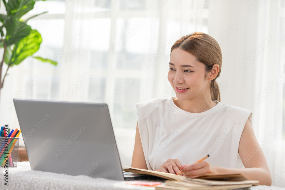 Smiling woman working on laptop at home, looking focused and productive during the day with natural light streaming in through windows. Smiling woman working on laptop at home, looking focused and productive during the day with natural light streaming in through windows.
