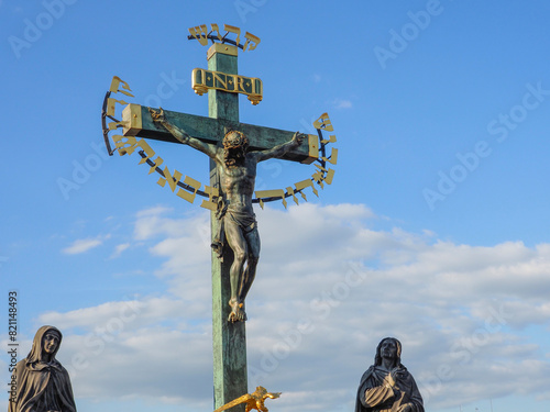Beautiful bronze statue of the crucifixion of Jesus Christ. Statue of the Holy Cross with Calvary Charles Bridge, sunny day clear sky