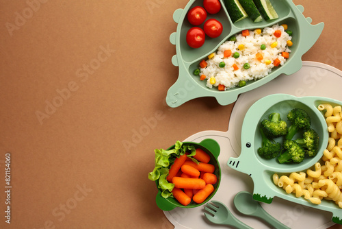 Kid-Friendly Healthy Meals. Nutritious meals served on animal-shaped plates. Features a dinosaur plate with tomatoes, cucumbers, and rice, a elephant plate with broccoli and pasta, and bowl of carrots photo