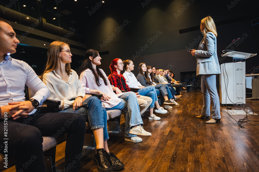 Female CEO having speech on press conference in convention center. Group of multiracial colleagues listening. Female CEO having speech on press conference in convention center. Group of multiracial colleagues listening.