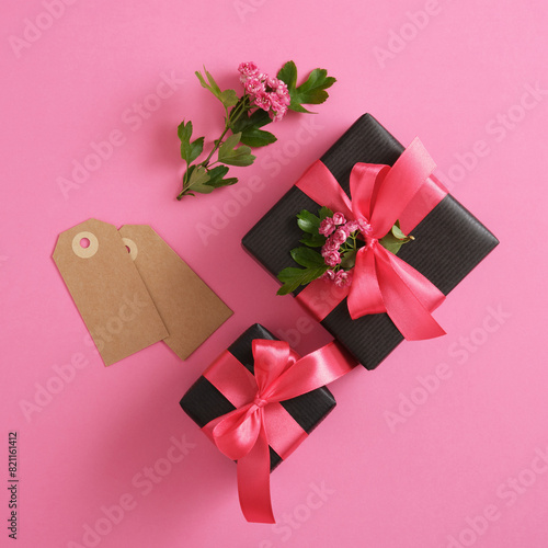 Set of black craft gift boxes with hawthorn flowers and pink ribbons.