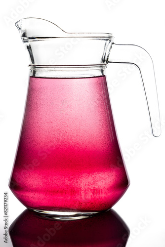 Obraz na płótnie Transparent glass jug with red, translucent drink. A pitcher on a white background, photograph taken against the light w salonie