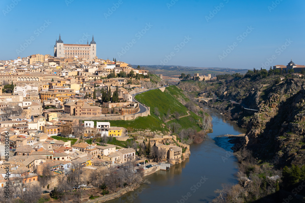 Fototapeta premium views of the impressive walled city of Toledo surrounded by the Tagus River. The imposing ancient castle Alcazar at the top.