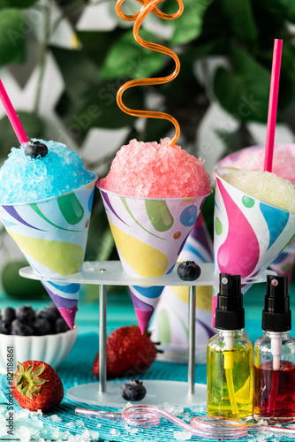 A close up of snow cones with fruit flavoured syrup.