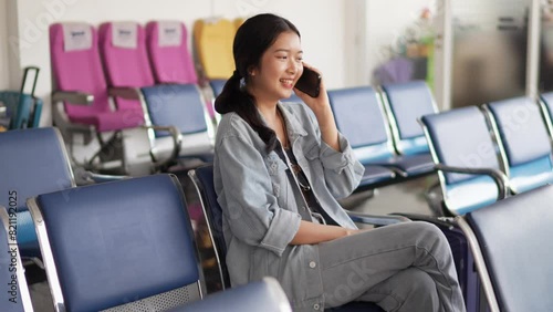 An Asian female tourist is using social media on her smartphone while waiting to travel abroad by airplane photo