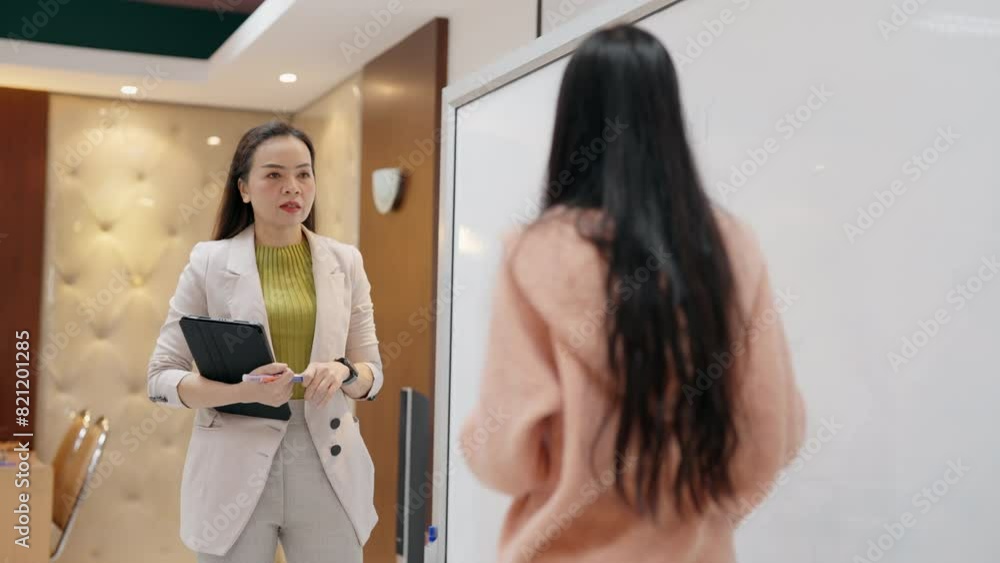 A woman in a suit is talking to another woman in a pink sweater. Scene is professional and serious A woman in a suit is talking to another woman in a pink sweater. Scene is professional and serious