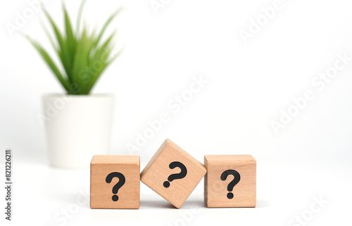3 wooden cubes with Questions mark sign on table with a pot of green plant on white background. The symbol written is ? acronym. Start of child or kid learning counting concept.Front View, Copy space.