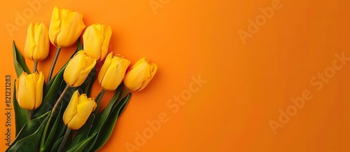 Photo of A bouquet of yellow tulips on an orange background, with copy space for text. Web banner showing the top view of a minimalistic floral composition. Flat lay style. Bright and airy color palet #821231283