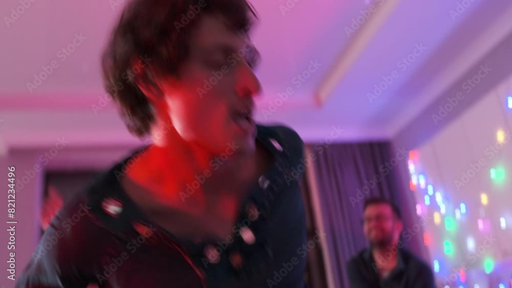 Group of friends line dancing together at home party, dynamic movements of friends getting down dance to beats music in neon lights. Close up. Group of friends line dancing together at home party, dynamic movements of friends getting down dance to beats music in neon lights. Close up.