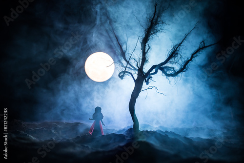 Alone girl in the dead forest at misty night. Silhouette of girl standing between trees under moonlight. Horror Halloween concept.