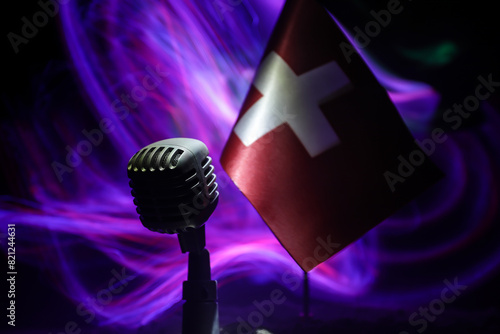 Microphone on a background of a blurry flag of Switzerland close-up. dark table decoration