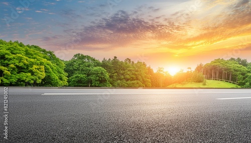 blurred background with asphalt road green forest and sunset on horizon