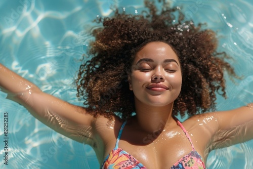 A woman with curly hair is floating in a pool © top images