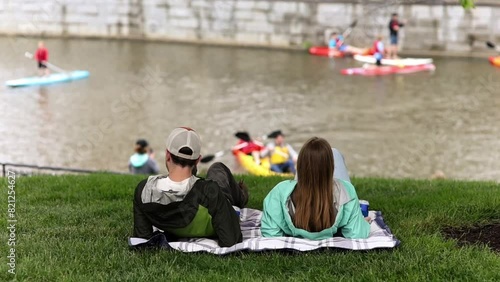 Group of Friends on Blanket Relaxing by The River with A Drink Overlooking Paddlers