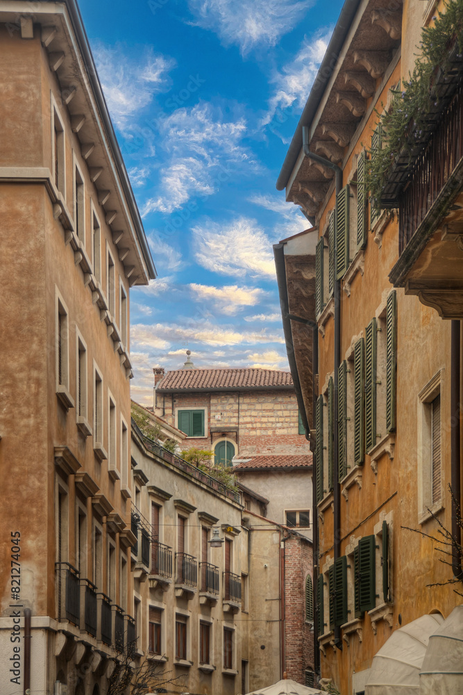 A view from inside on of the streets of Verona - Italy looking up at the sky with the facades of the buildings 