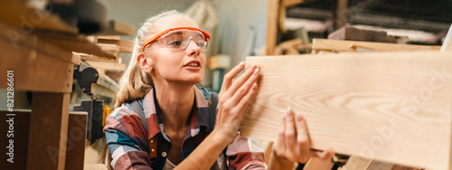 Slika na platnu Attractive middle aged woman carpenter designer works with ruler, make notches on the tree in workshop