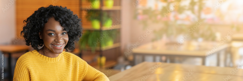 Portrait of black young cheerful lady with hair relaxing at cafeteria, drinking tea, panorama with copy space Portrait of black young cheerful lady with hair relaxing at cafeteria, drinking tea, panorama with copy space