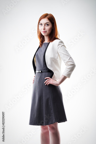 Auburn-haired woman stands confidently, business attire