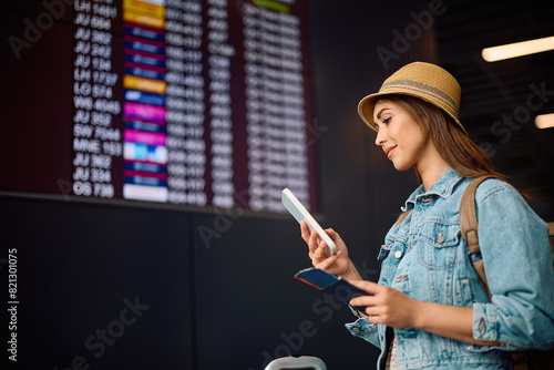 Foto Smiling traveler checking her boarding time on mobile phone at airport