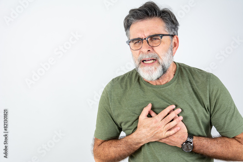 Senior man is having pain in his chest. Heart attack symptoms. Mature man holding his heart in pain. Healthcare concept. Man suffering from chest pain with painful expression	
