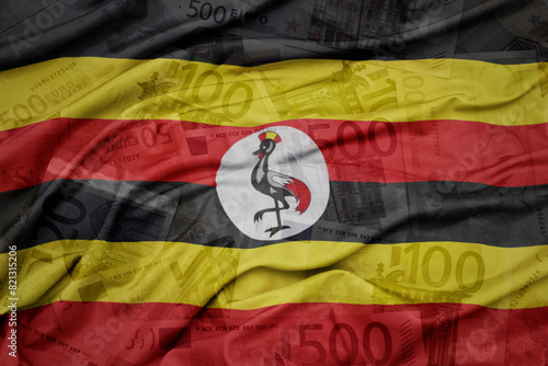 waving colorful national flag of uganda on a euro money banknotes background. finance concept.