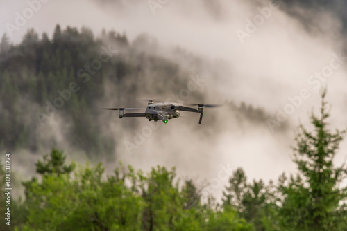 Drone with camera flying over mountain fields.