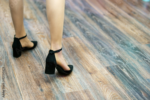 Women's feet in suede shoes on a laminated floor
