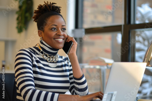 Woman Sitting in Front of Laptop Talking on Cell Phone