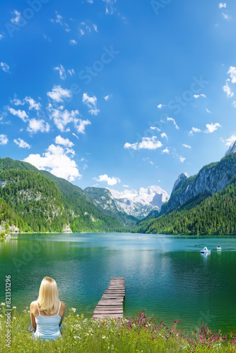 A woman enjoys a scenic picture postcard view of Gosauseen, Austria reflecting in the lake.