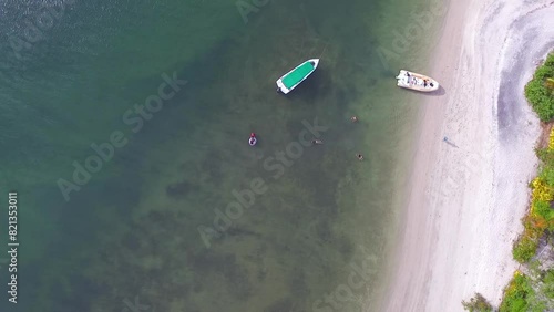 Pessoas em lanchas tomando banho de mar em praia paradisíaca de uma pequena ilha na Bahia, Brasil. Imagem aérea azimutal de um drone voando alto. photo