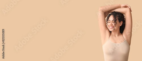 Beautiful young African-American woman on beige background with space for text. Concept of using deodorant