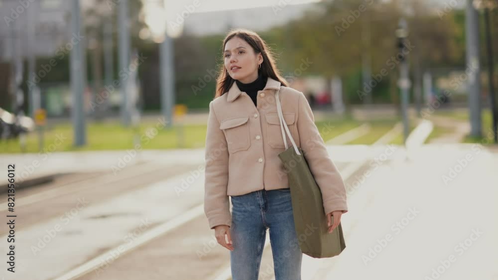 Casually dressed young woman expecting a bus at a quiet station on a bright, sunny day. Casually dressed young woman expecting a bus at a quiet station on a bright, sunny day.