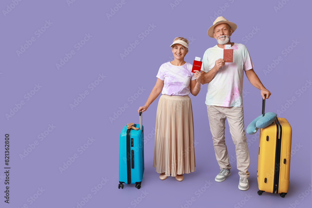 Mature couple of travelers with passports and suitcases on lilac background Mature couple of travelers with passports and suitcases on lilac background