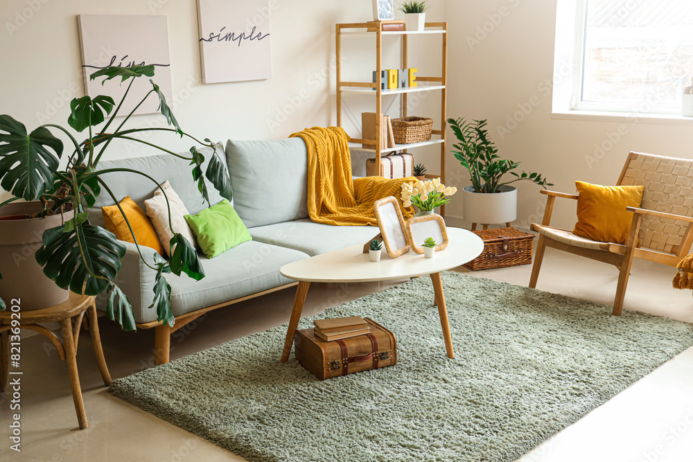Obraz premium Interior of stylish living room with sofa, posters and frames on table