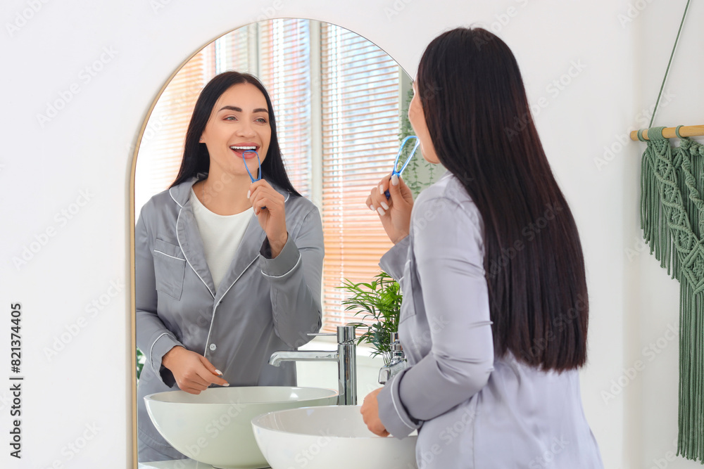 Beautiful young happy woman with tongue scraper in bathroom at home Beautiful young happy woman with tongue scraper in bathroom at home