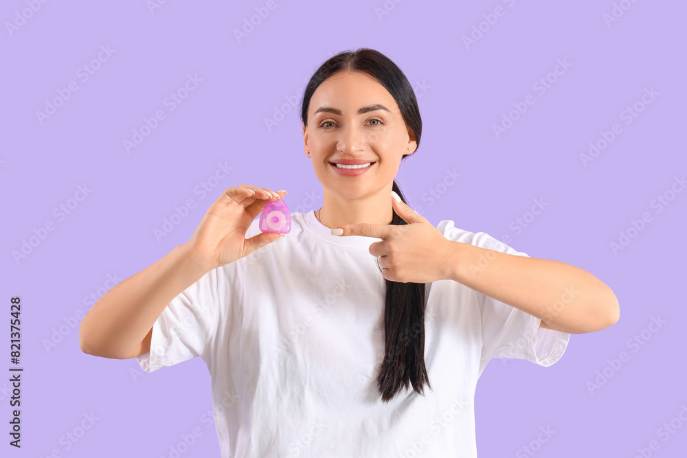 Beautiful young happy woman pointing at dental floss on purple background Beautiful young happy woman pointing at dental floss on purple background