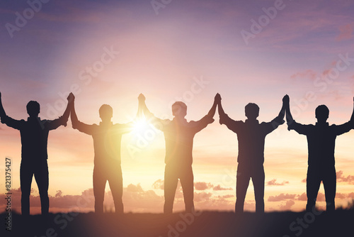 Silhouette of people holding hands against sunset background, concept of peace and victory