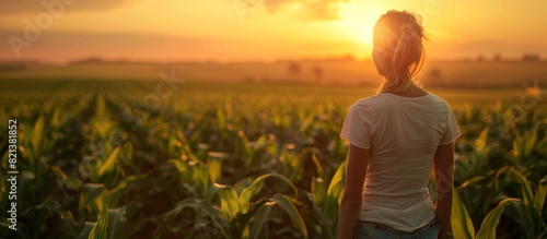 Woman standing in corn field at sunset