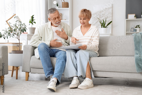Mature deaf mute couple reading newspaper on sofa at home photo